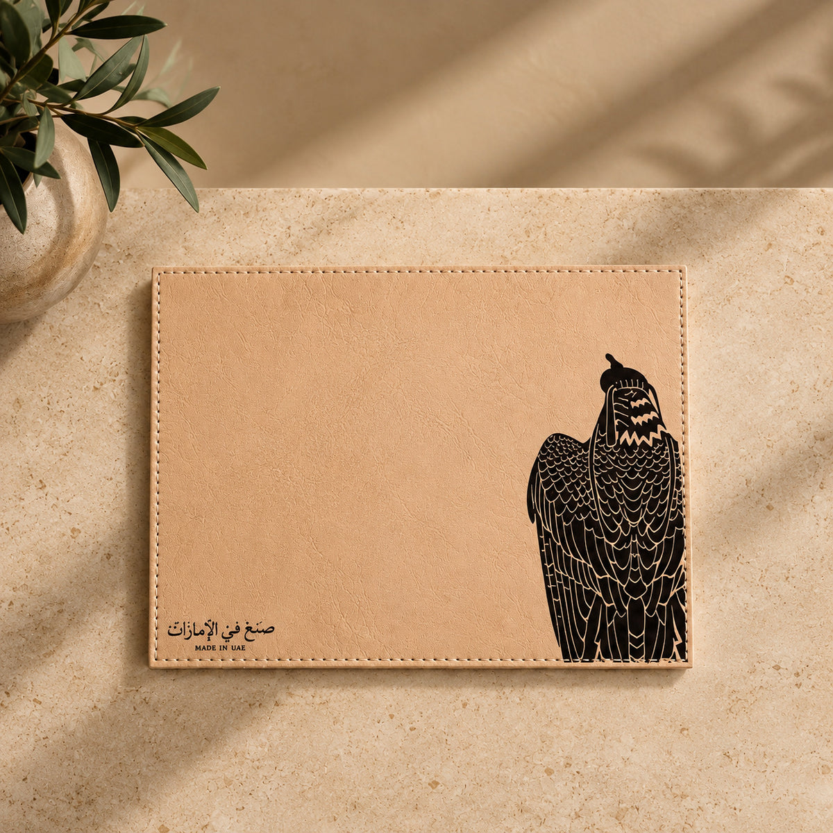قاعدة أكواب قهوة من الجلد البيج بسماكة 4 ملم، برسم الصقر وعبارة صنع في الإمارات، بدون أدوات.